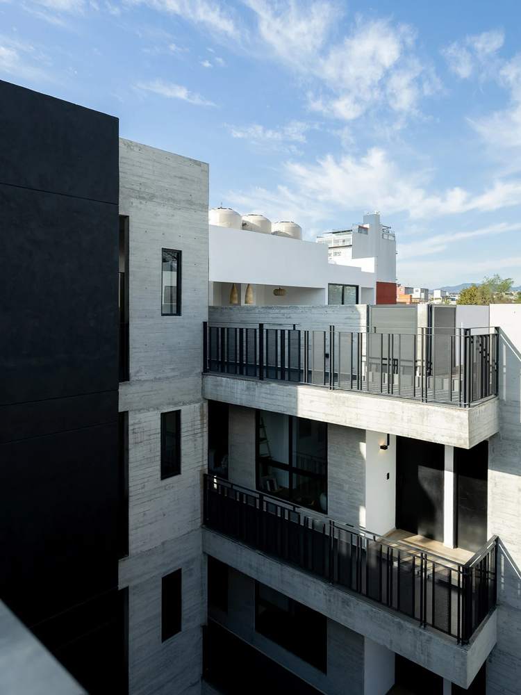 Fachada de concreto blanco y herrería negra de Comercio 51